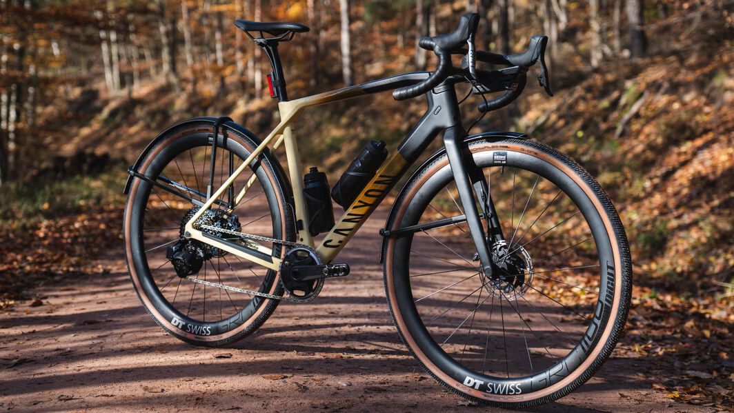 Canyon Grail Gravel Bike Geometry – All-Terrain Riding in Autumn Canyon Grail gravel bike with dual handlebar design, shown on a leaf-covered forest trail, designed with endurance-focused geometry for gravel riding.