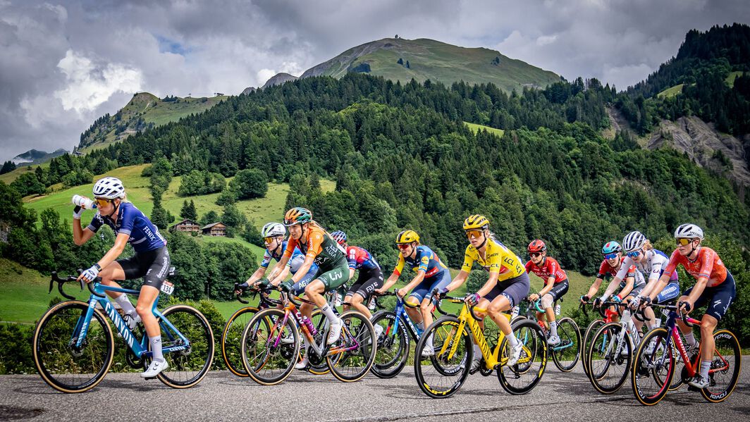 Pro women’s peloton climbs through scenic mountains during Tour de France Femmes, led by riders on Canyon bikes.