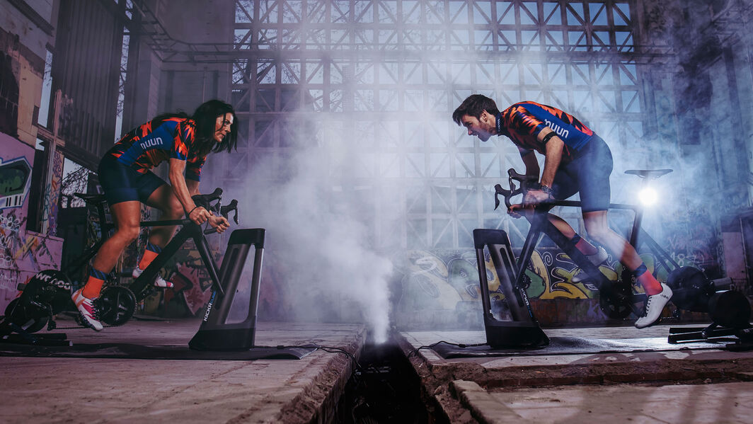 Two riders face each other on their turbo trainers in a battle on Zwift Two riders face each other on their turbo trainers in a battle on Zwift